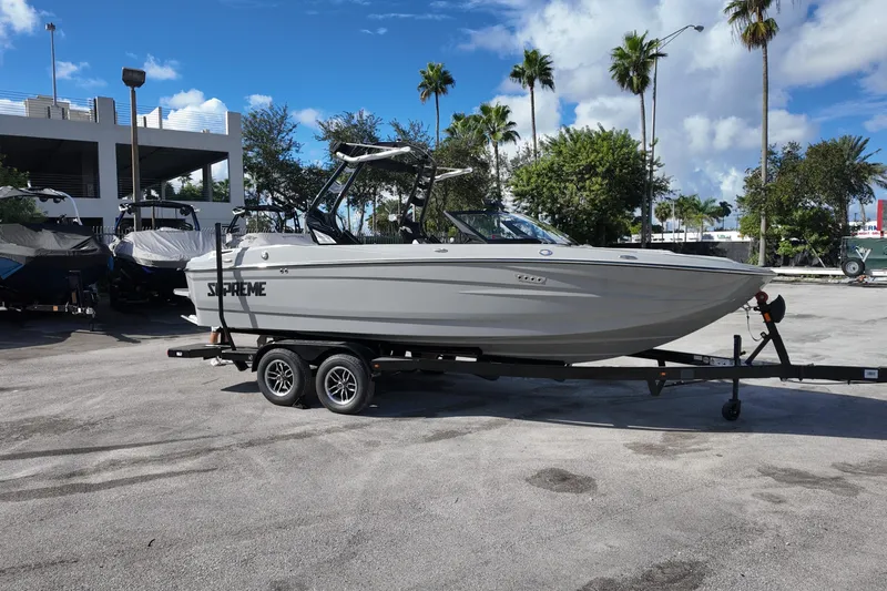  Yacht Photos Pics 2025 Supreme S220 boat on trailer, parked outdoors under a clear blue sky.
