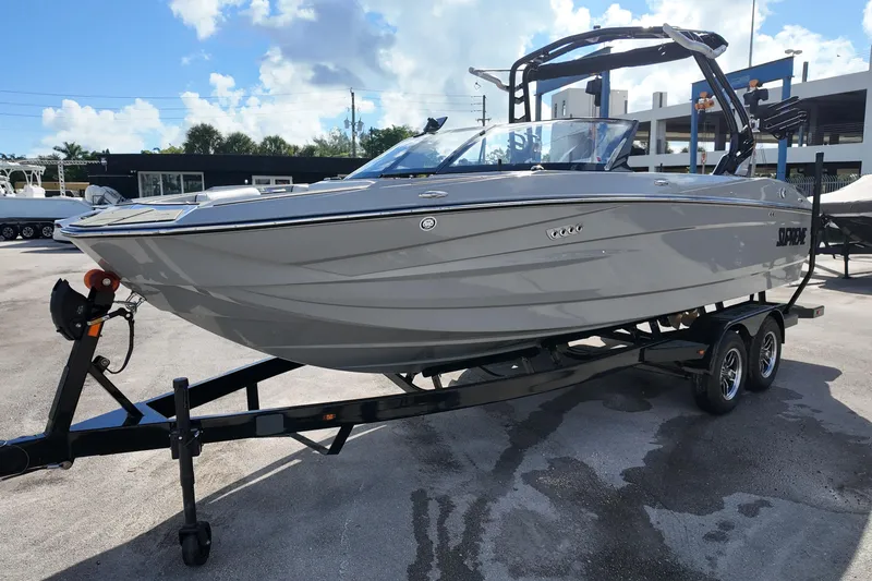  Yacht Photos Pics 2025 Supreme S220 boat on trailer, sleek design, parked outdoors under blue sky.