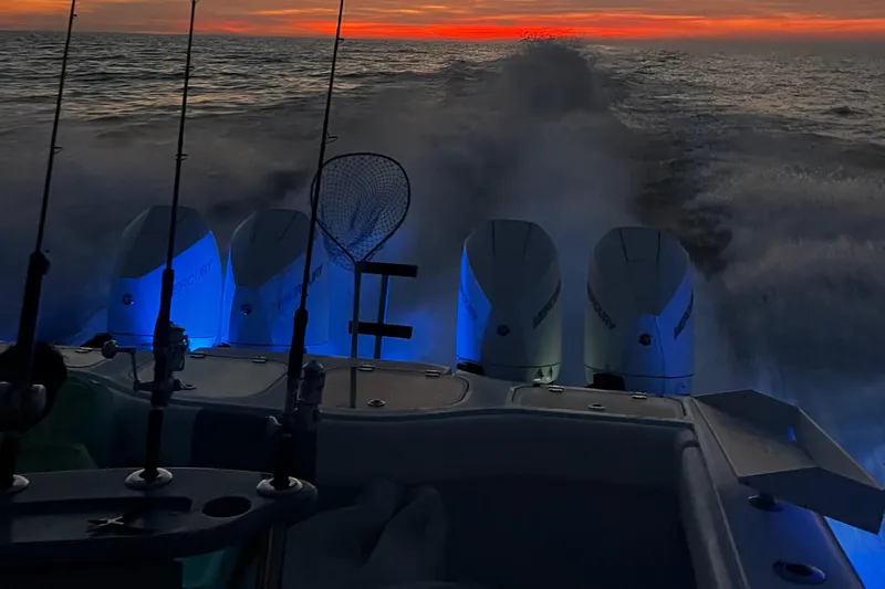 Necessity Yacht Photos Pics Freeman 42LR boat at sunset, four engines, fishing rods, and net visible.