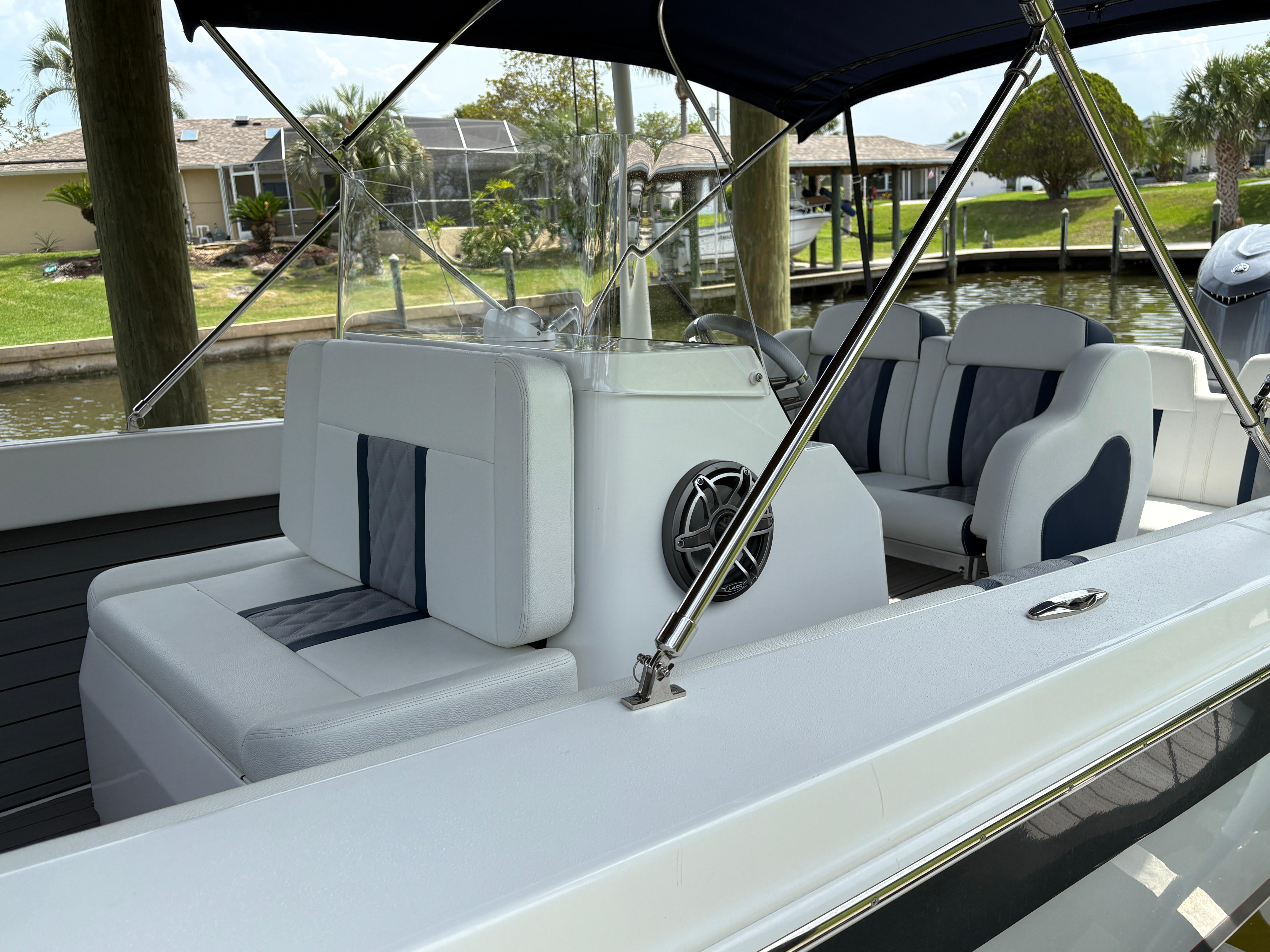 Luxury boat interior with white and blue seating, 2023 Action 25 model, docked by a canal.
