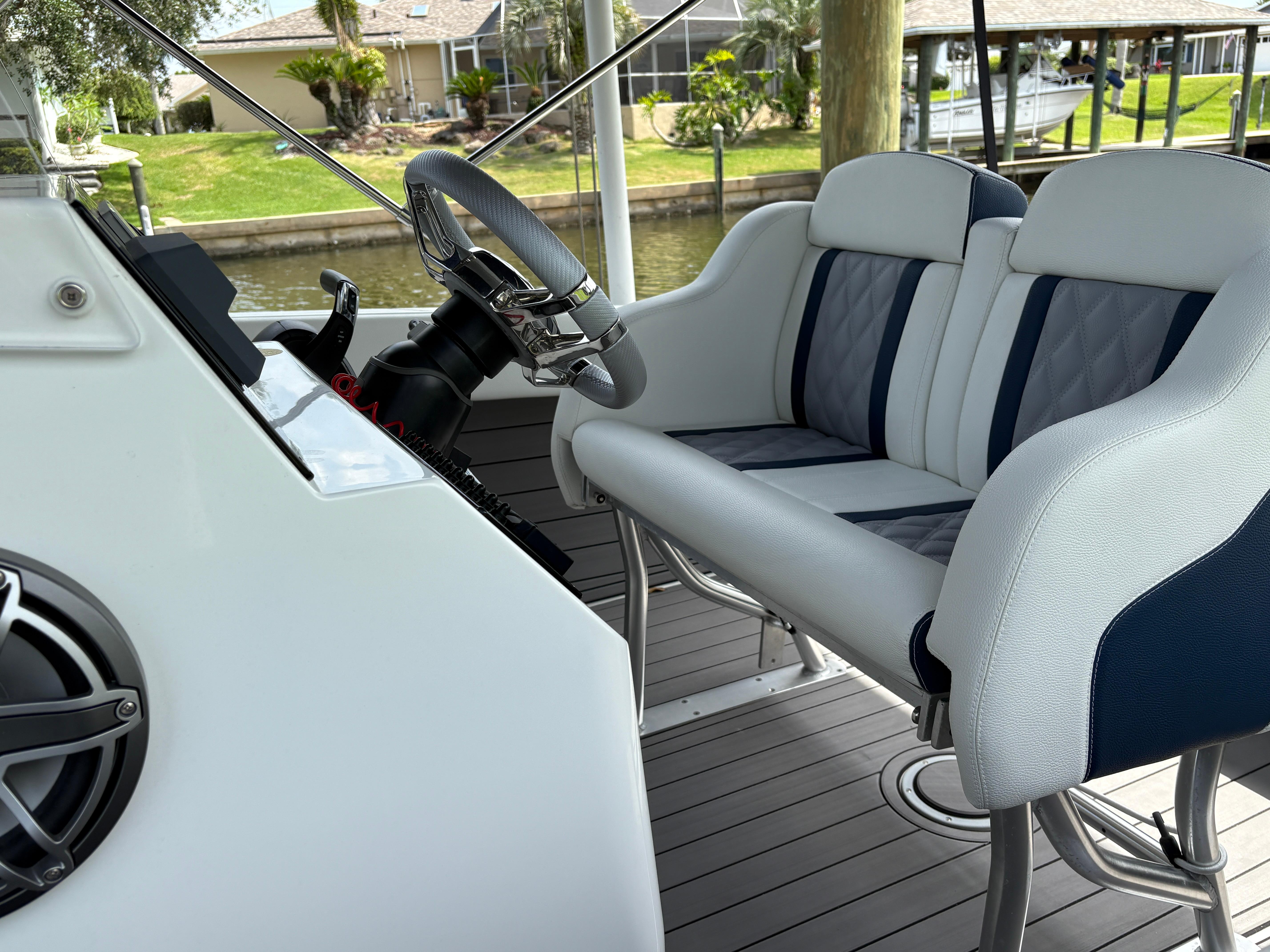 Luxury boat interior with modern steering and cushioned seating, Action 25 model, 2023.