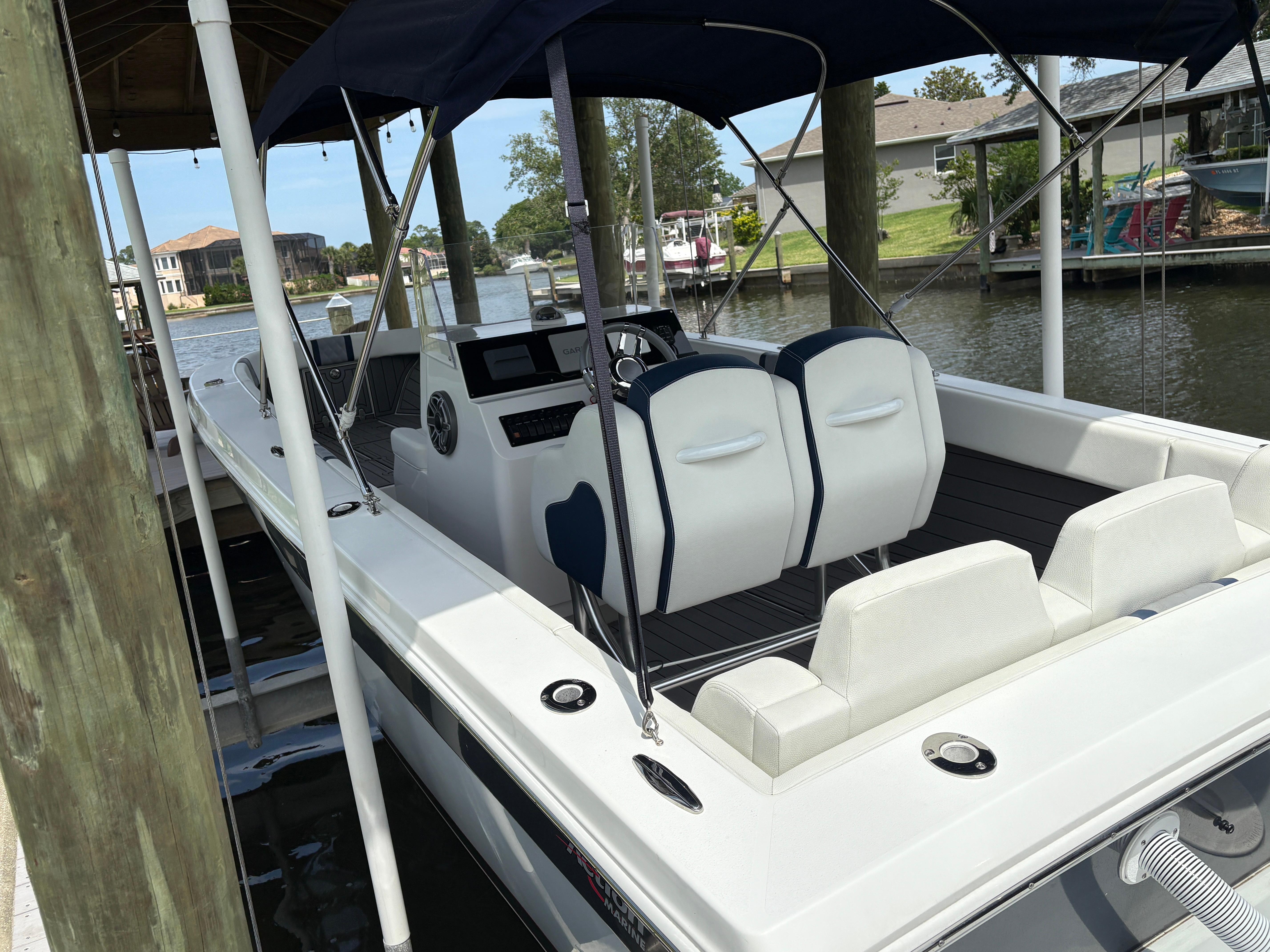 2023 Action 25 boat docked, featuring sleek design and comfortable seating under a canopy.