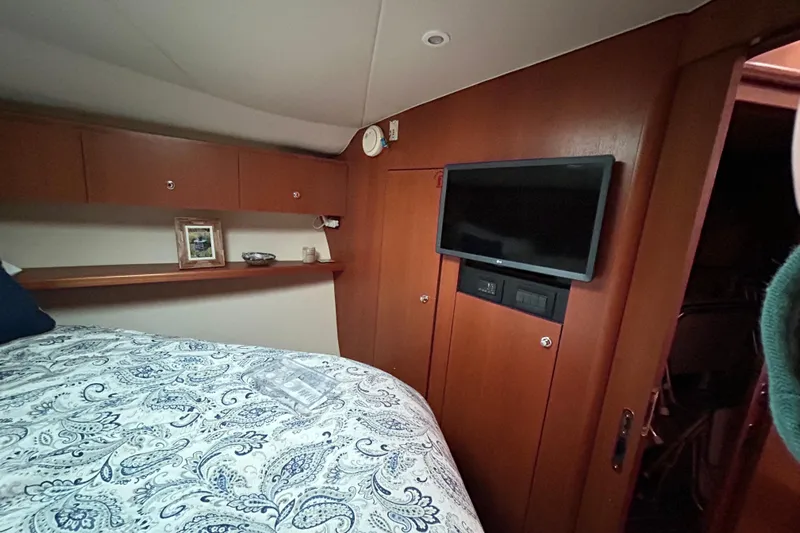 Follow That Stern Ix Yacht Photos Pics 2007 Tiara Yachts 3900 Convertible cabin with TV, wooden cabinets, and patterned bedding.
