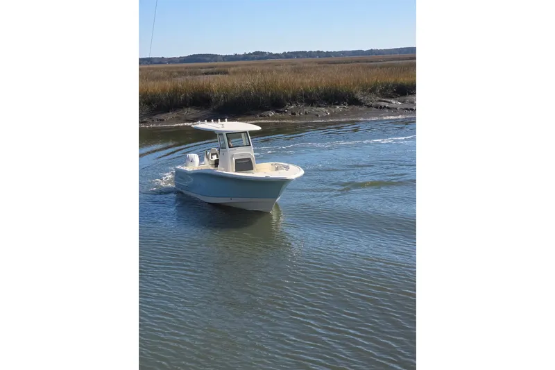  Yacht Photos Pics 2026 Pioneer boat navigating calm waters near grassy shoreline.