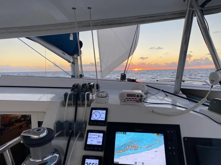 Hh Sound Waves Yacht Photos Pics Lagoon 420 Hybrid sailing at sunset, featuring navigation equipment and ocean view.