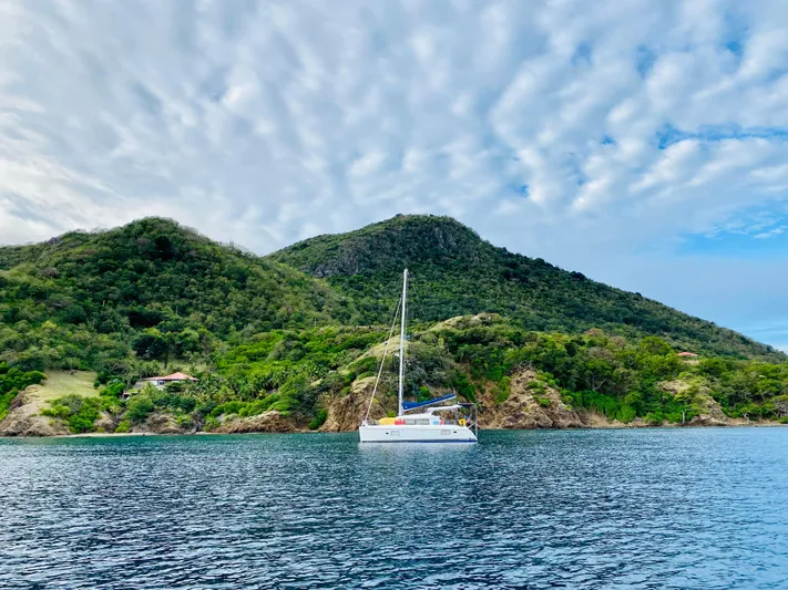 Hh Sound Waves Yacht Photos Pics Sailboat Lagoon 420 Hybrid 2008 anchored near lush green island under cloudy sky.