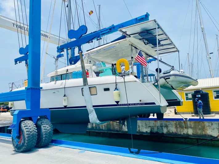 Hh Sound Waves Yacht Photos Pics 2008 Lagoon 420 Hybrid catamaran in marina lift, with American flag and dinghy.