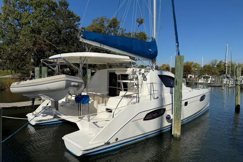 Way Maker Yacht Photos Pics 2010 Leopard 38 catamaran docked, featuring a blue sail and attached dinghy.