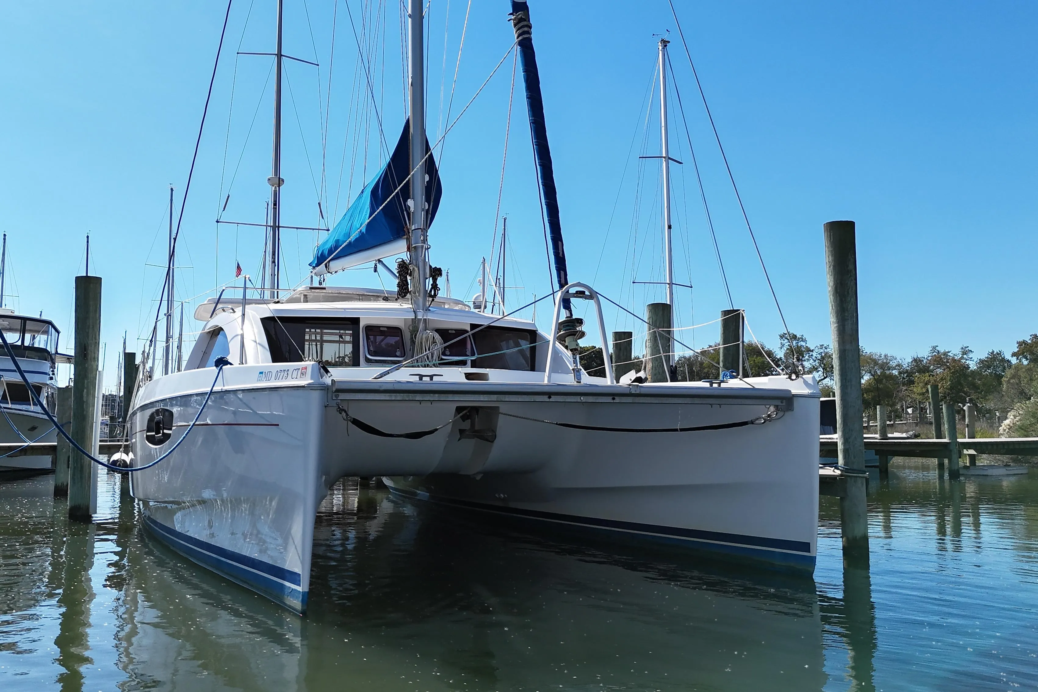 2010 Leopard 38 catamaran docked in a marina under clear blue skies.