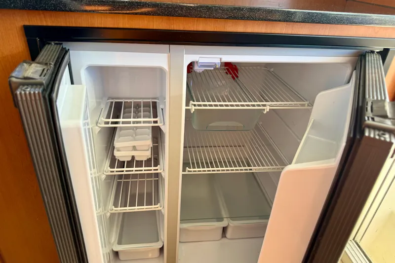 Way Maker Yacht Photos Pics Empty refrigerator in a 2010 Leopard 38 yacht, featuring open doors and wire shelves.