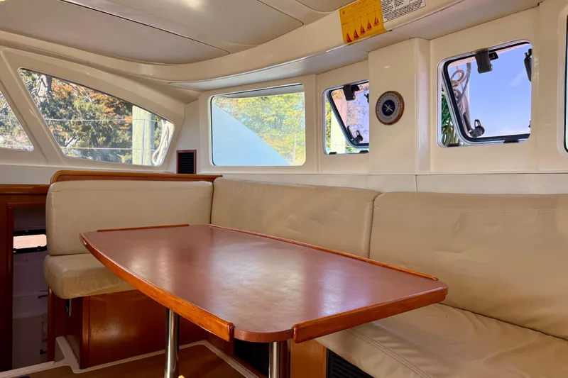 Way Maker Yacht Photos Pics Interior of 2010 Leopard 38 yacht with beige seating and wooden table.