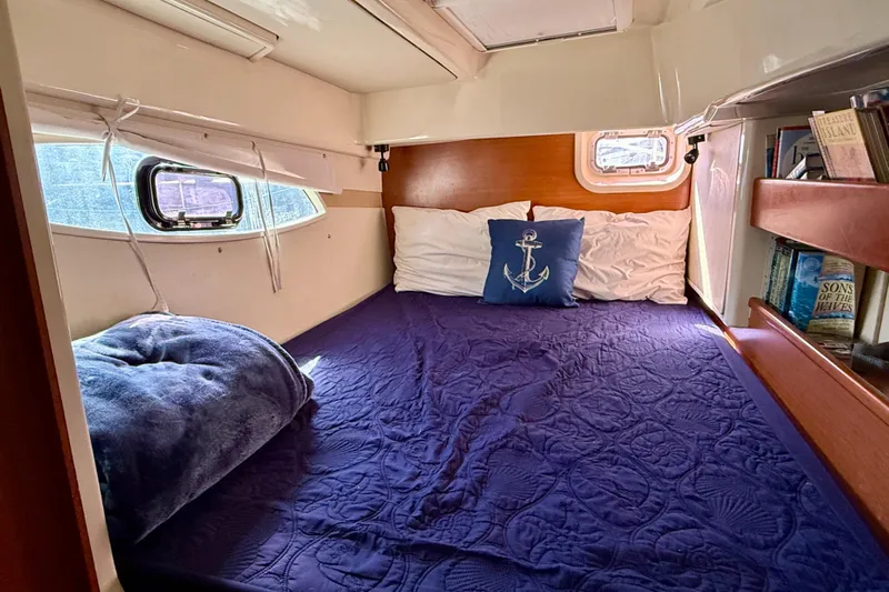 Way Maker Yacht Photos Pics Cozy cabin interior of 2010 Leopard 38 catamaran with nautical-themed bedding and books.