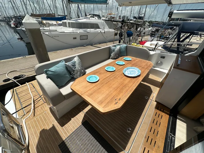 Nan Sea Cay Yacht Photos Pics 2020 Sealine C430 yacht with elegant outdoor seating and dining area, docked at marina.