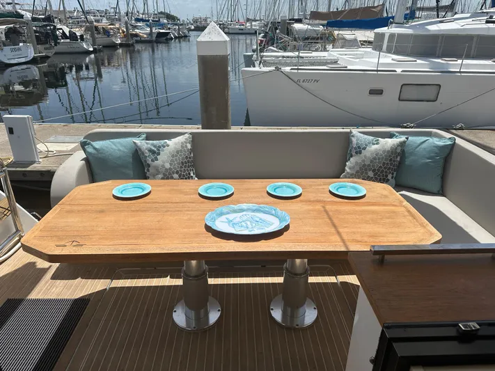 Nan Sea Cay Yacht Photos Pics Outdoor dining area on 2020 Sealine C430 yacht, featuring a wooden table with blue plates.