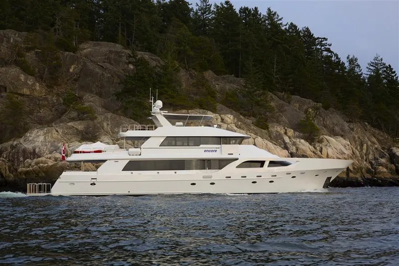 Encore Yacht Photos Pics Luxurious 1992 Crescent Custom yacht cruising near rocky shoreline and forested landscape.