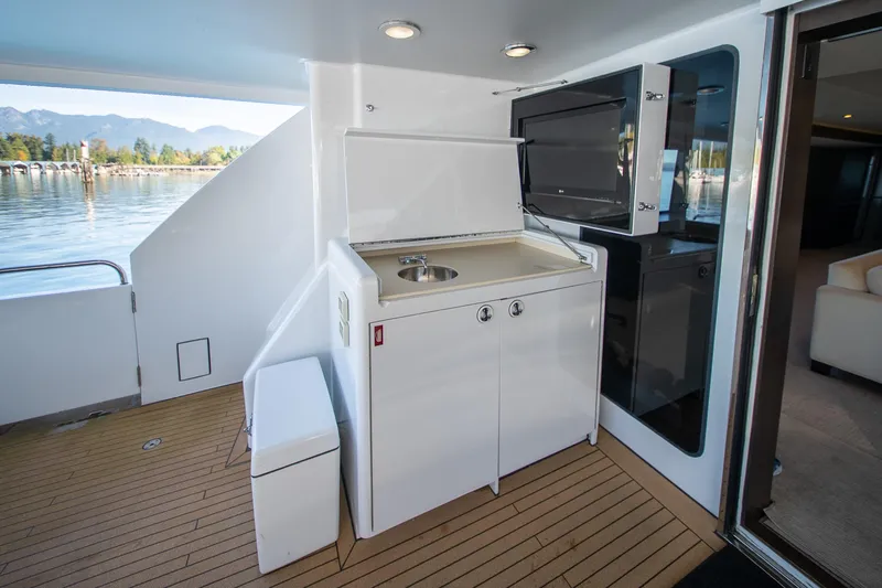 Encore Yacht Photos Pics Outdoor kitchenette on 1992 Crescent Custom yacht with sink and storage, overlooking serene waters.