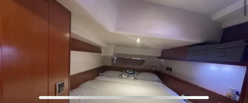  Yacht Photos Pics Interior cabin of 2011 Beneteau Oceanis 58 yacht, featuring a cozy bed and wooden accents.