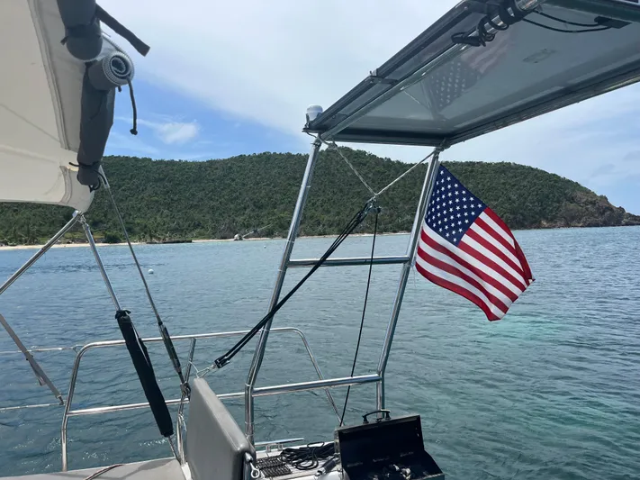  Yacht Photos Pics Beneteau Oceanis 58 sailboat, 2011 model, with American flag, anchored near lush coastline.
