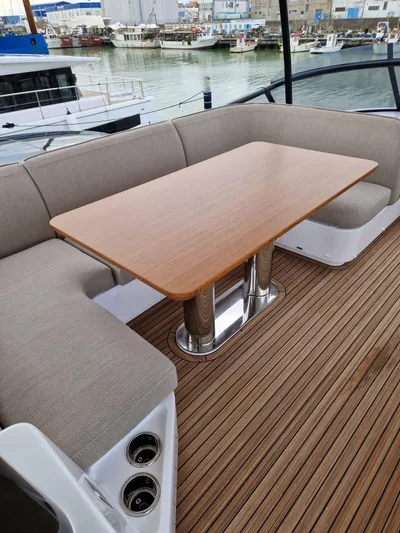  Yacht Photos Pics Luxury seating area on 2025 Azimut Magellano 60 yacht with wooden table and waterfront view.