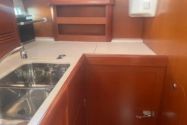 Plein Air Yacht Photos Pics Interior of 2006 Beneteau 423 yacht kitchen with wooden cabinetry and stainless steel sink.