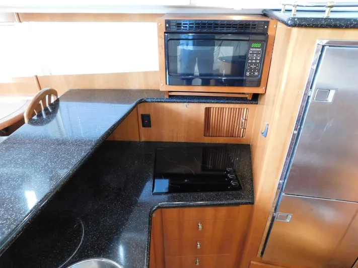 Justified Insanity II Yacht Photos Pics 2003 Carver 444 Cockpit Motor Yacht kitchen with microwave, stovetop, and sleek countertops.