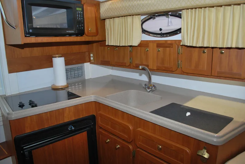  Yacht Photos Pics 2005 Stamas 370 Express boat kitchen with wooden cabinets, microwave, and sink.