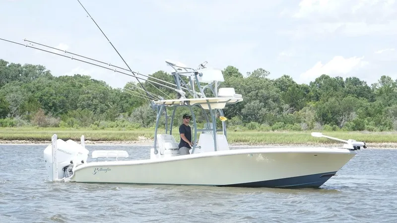  Yacht Photos Pics 2020 Yellowfin 26 Hybrid boat on water, featuring fishing rods and lush green shoreline.