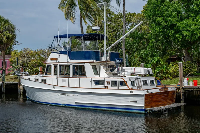Grande Jete Yacht Photos Pics 1990 Grand Banks 46 Classic yacht docked by lush greenery and palm trees.