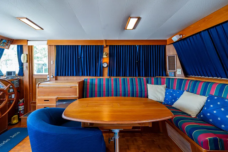 Grande Jete Yacht Photos Pics Interior of 1990 Grand Banks 46 Classic yacht with wooden table and striped seating.