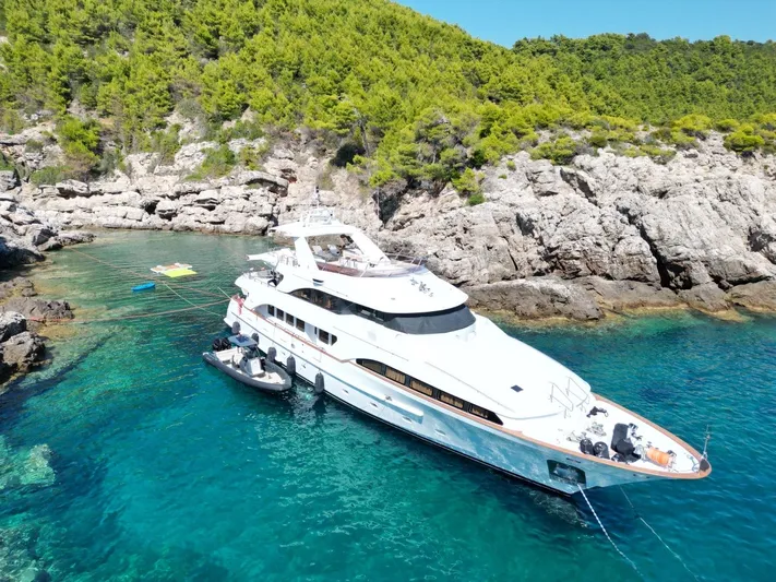 Frienship Yacht Photos Pics Luxurious 2000 Benetti Classic 115 yacht anchored in a serene, rocky cove.