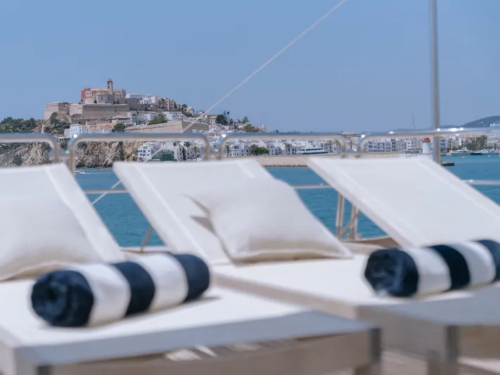Frienship Yacht Photos Pics Sun loungers on Benetti Classic 115 yacht, overlooking coastal fortress and blue sea.