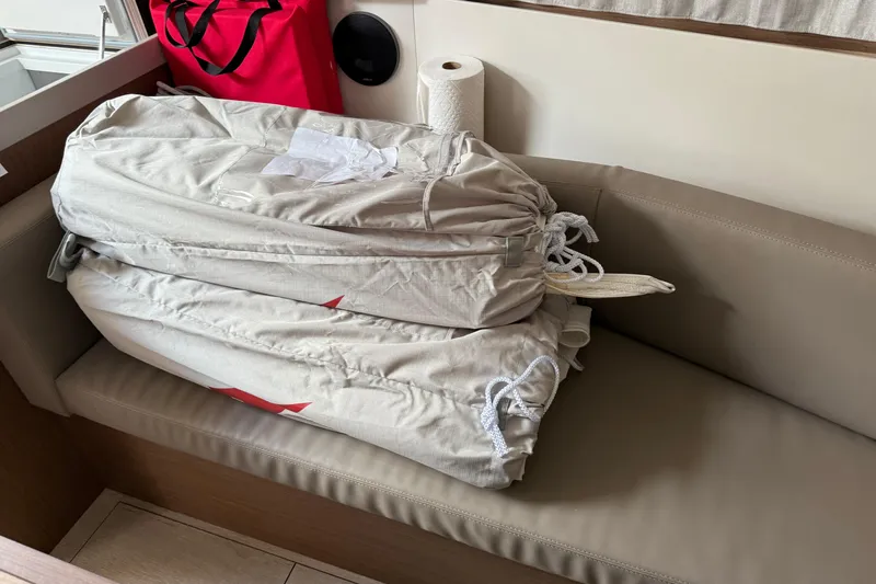  Yacht Photos Pics Beneteau Oceanis 35.1 interior with stacked sail bags on beige seating, 2021 model.