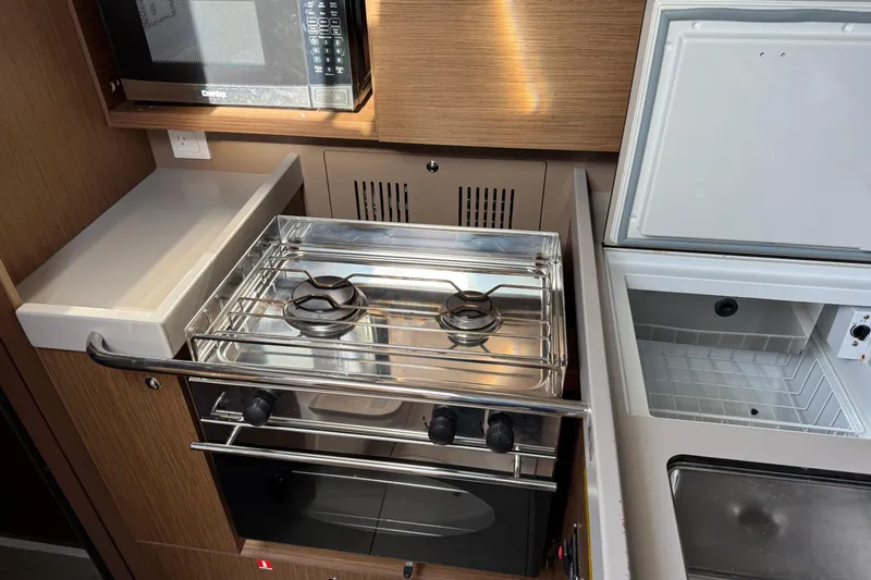  Yacht Photos Pics Compact kitchen area in a 2021 Beneteau Oceanis 35.1 yacht with stove and microwave.