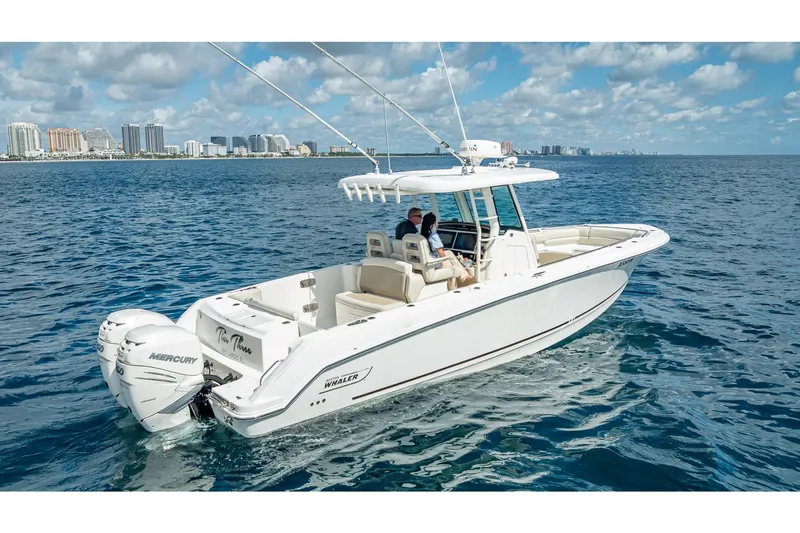 330 Boston Whaler Yacht Photos Pics 2017 Boston Whaler 330 Outrage boat cruising on ocean with city skyline in background.
