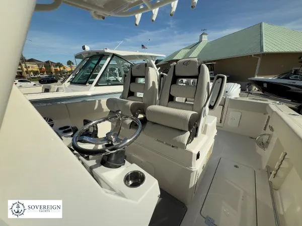 312-027 Yacht Photos Pics 2024 Sailfish 312 boat interior with dual captain's chairs and steering wheel, Sovereign Yachts logo.