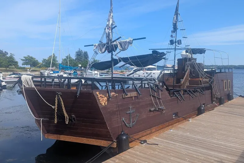  Yacht Photos Pics Custom 2015 pirate ship docked at a marina, featuring wooden hull and black sails.