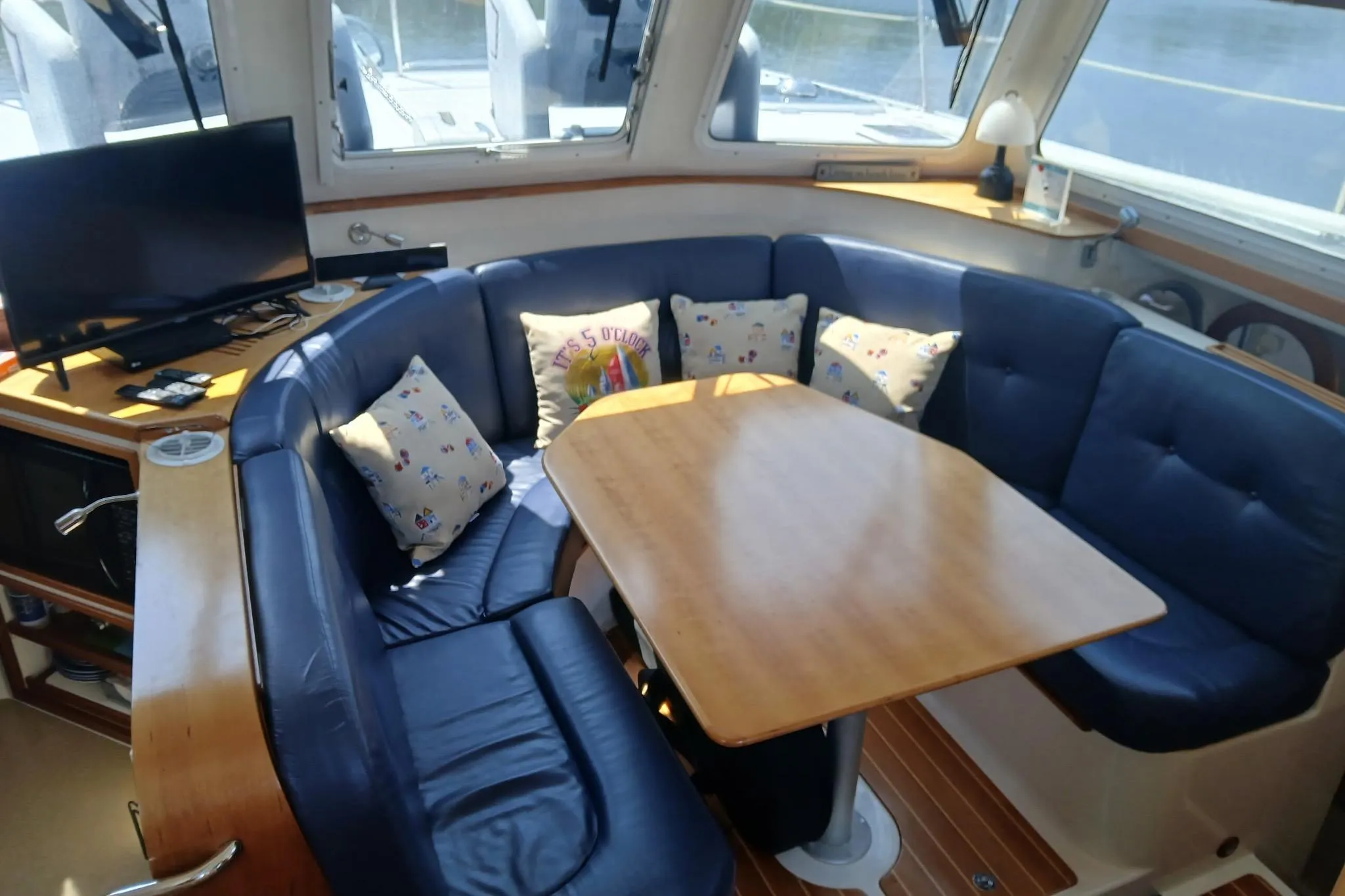 2006 PDQ PowerCat interior with blue seating, wooden table, and TV setup.