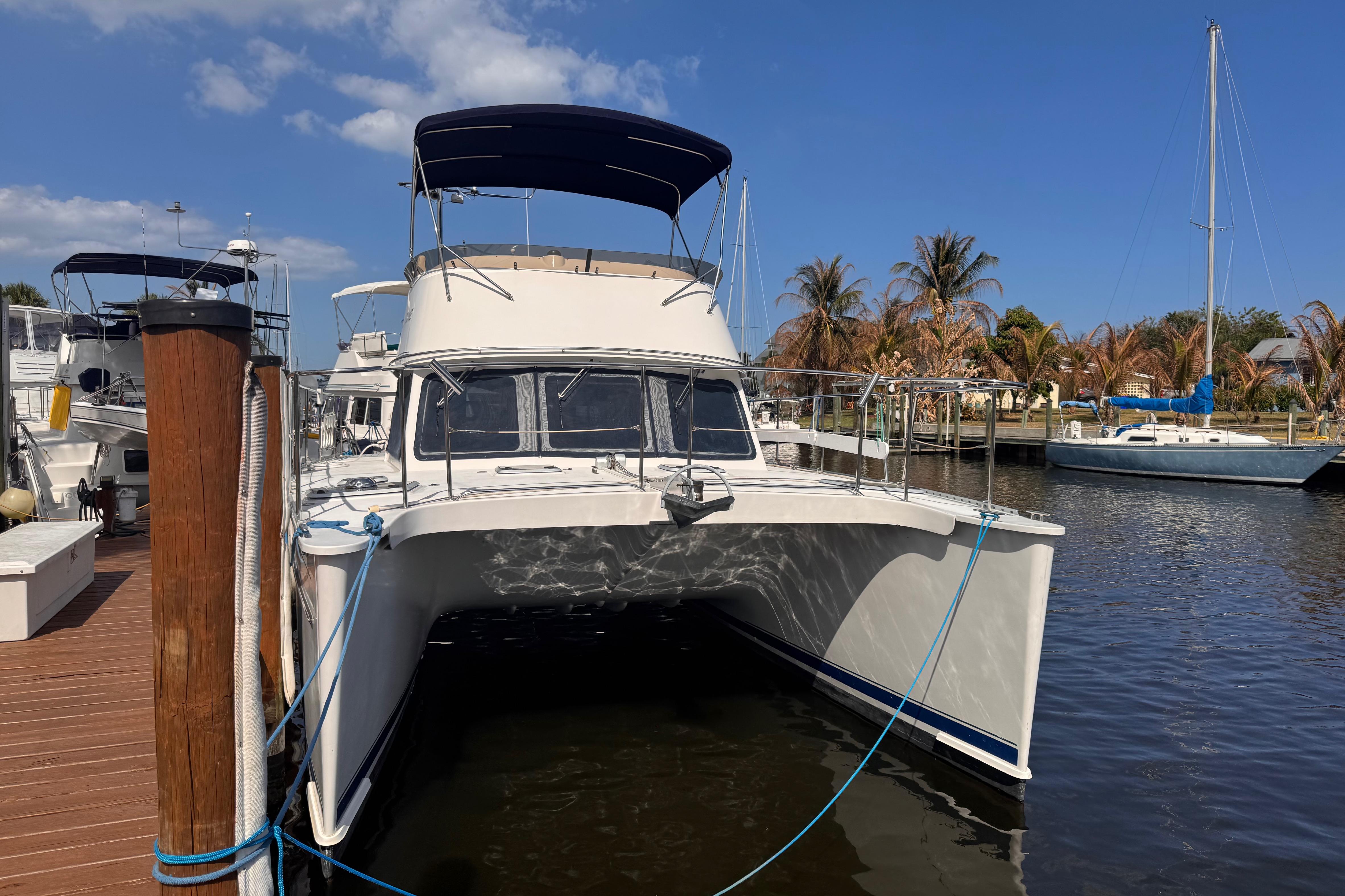 2006 PDQ PowerCat docked at marina with clear blue sky.