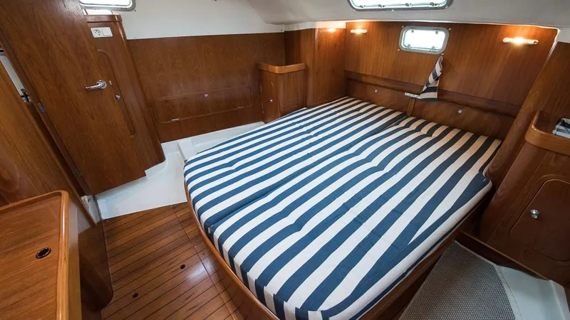 1730 Yacht Photos Pics 1999 Beneteau Oceanis Clipper 44 CC cabin with striped bedding and wooden interior.