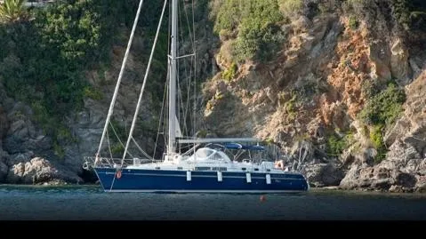 1730 Yacht Photos Pics 1999 Beneteau Oceanis Clipper 44 CC sailboat anchored near rocky coastline.