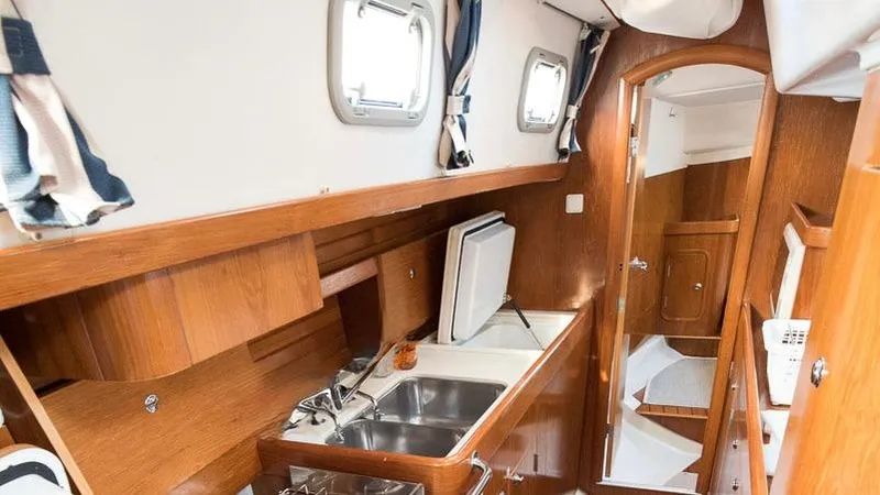 1730 Yacht Photos Pics Interior of 1999 Beneteau Oceanis Clipper 44 CC yacht, featuring wooden cabinetry and compact kitchen.