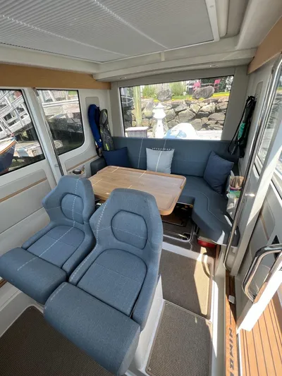 Crosswinds Yacht Photos Pics Interior of 2023 Nimbus C9 boat with blue seating and wooden table.