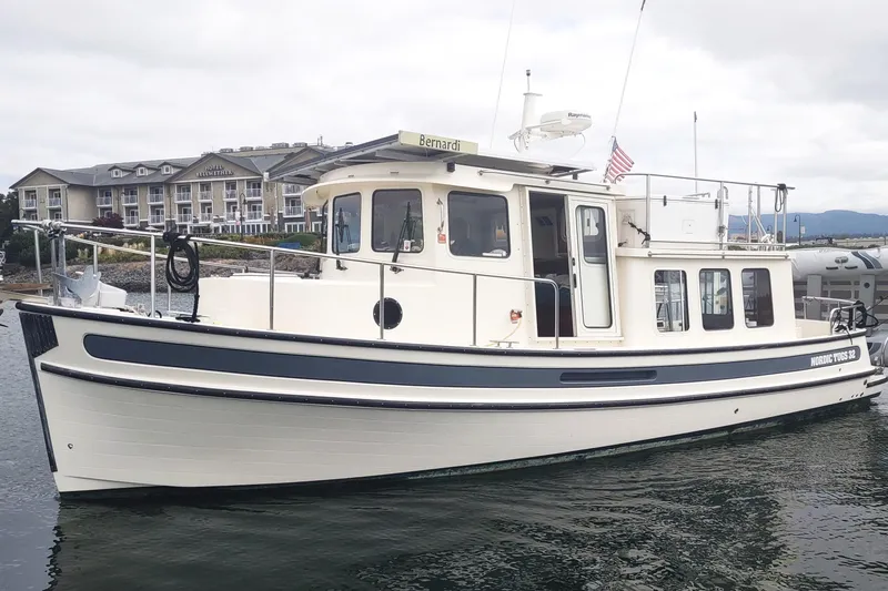 Bernardi Yacht Photos Pics 2004 Nordic Tug 32 boat docked near a waterfront hotel.