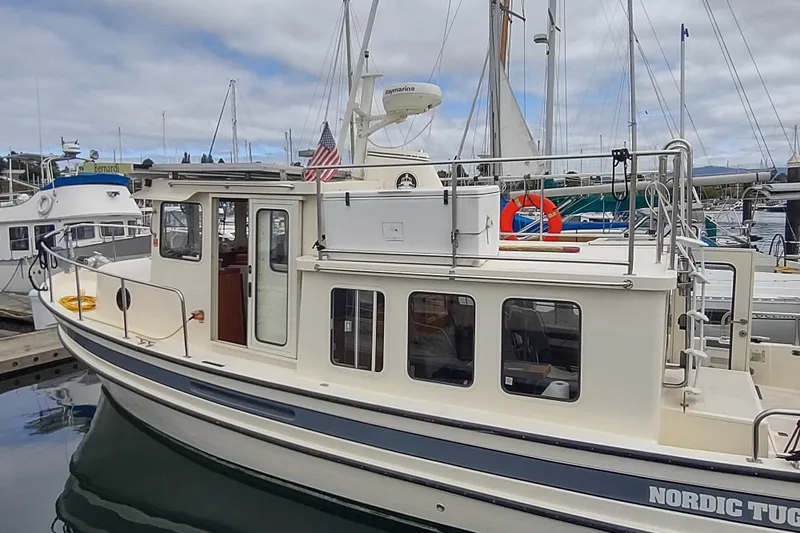Bernardi Yacht Photos Pics 2004 Nordic Tug 32 docked at marina, featuring classic design and American flag.