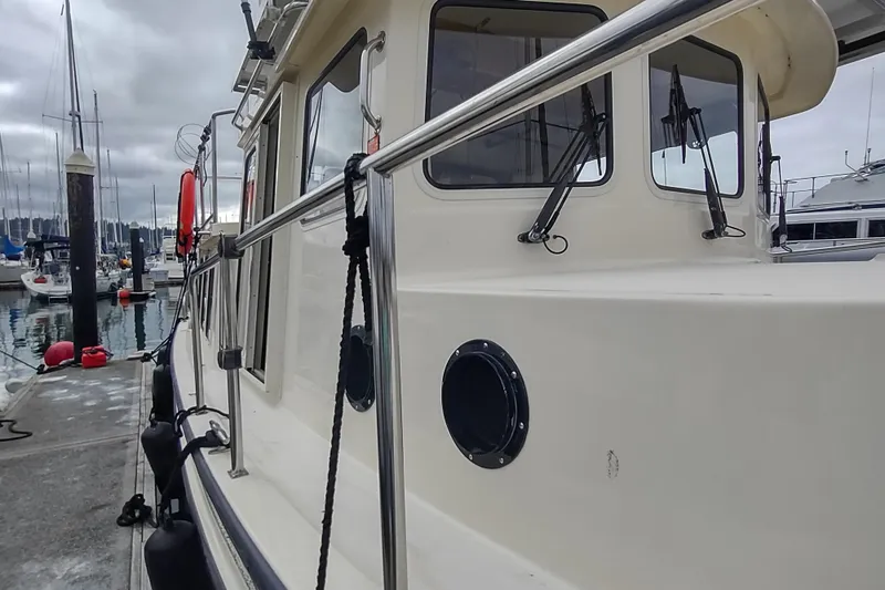 Bernardi Yacht Photos Pics 2004 Nordic Tug 32 docked at marina, showcasing side view and cabin windows.