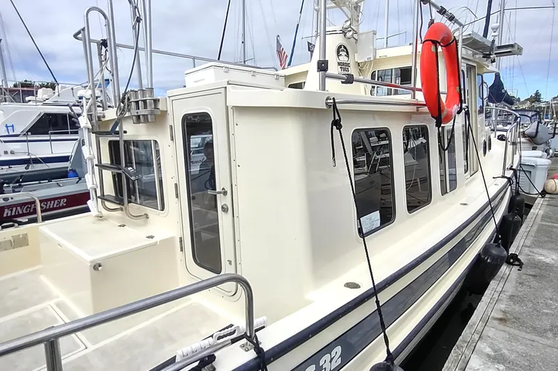 Bernardi Yacht Photos Pics 2004 Nordic Tug 32 docked, featuring a cream exterior and red life preserver.