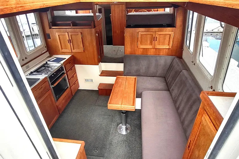 Bernardi Yacht Photos Pics Interior of 2004 Nordic Tug 32 with cozy seating, wooden cabinetry, and compact kitchen.