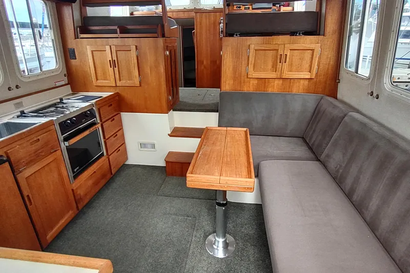 Bernardi Yacht Photos Pics 2004 Nordic Tug 32 interior with wood cabinetry, compact kitchen, and cozy seating area.
