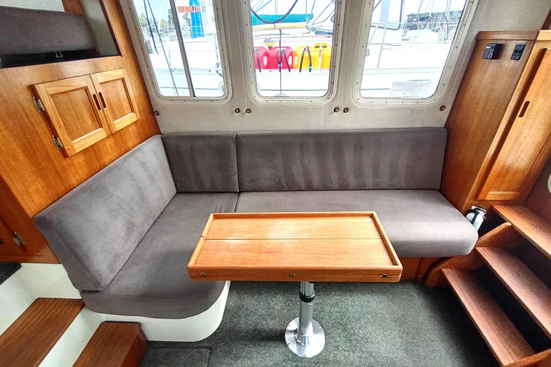 Bernardi Yacht Photos Pics Cozy interior of 2004 Nordic Tug 32 with wooden table and gray seating.