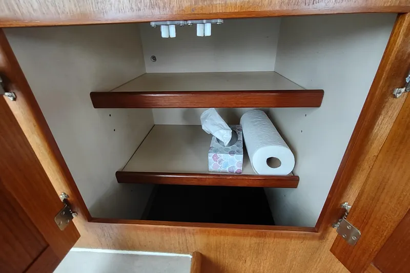Bernardi Yacht Photos Pics Open wooden cabinet with shelves, tissue box, and paper towel roll on a 2004 Nordic Tug 32.